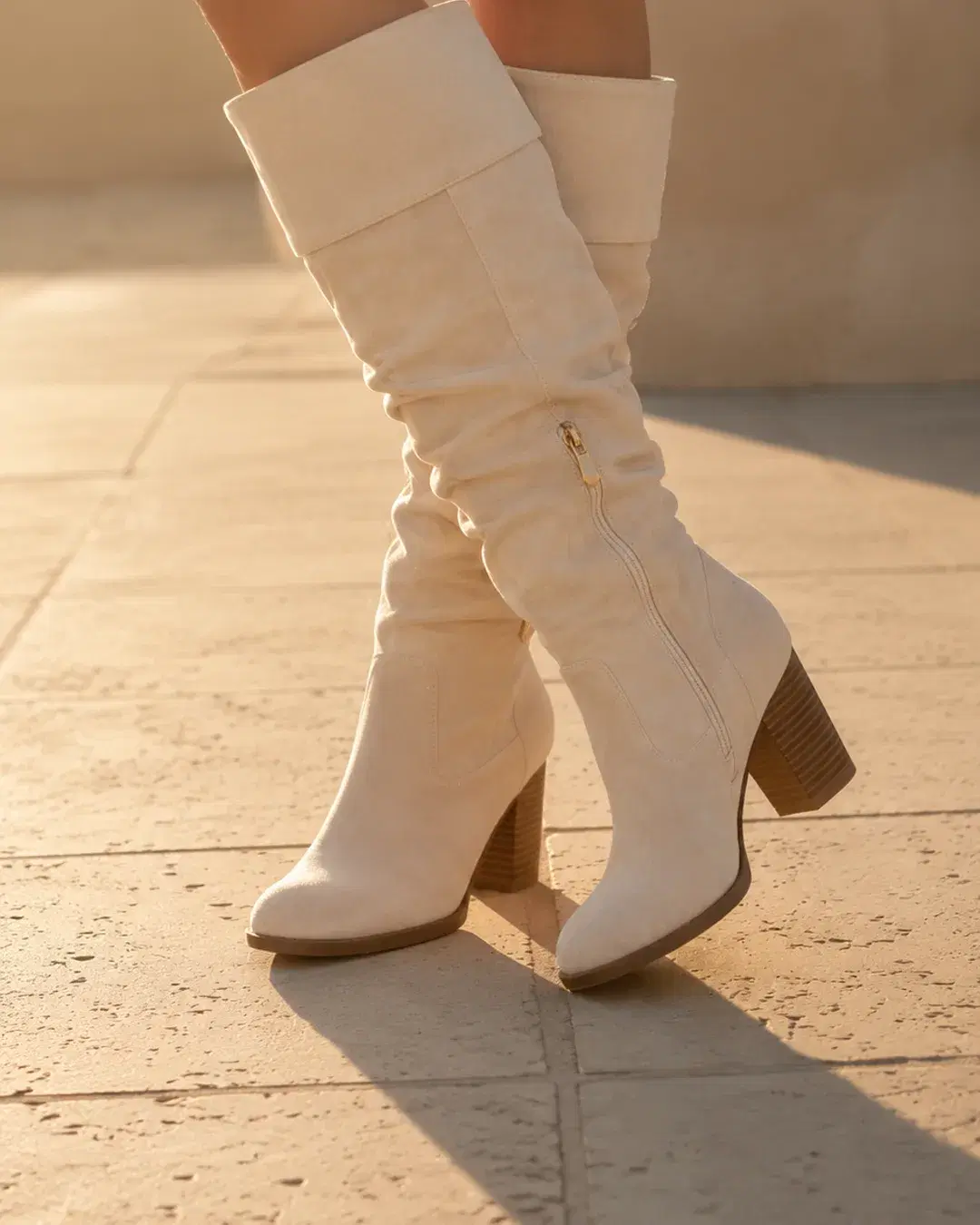 Both boots standing unworn on a warm pale stone terrace
