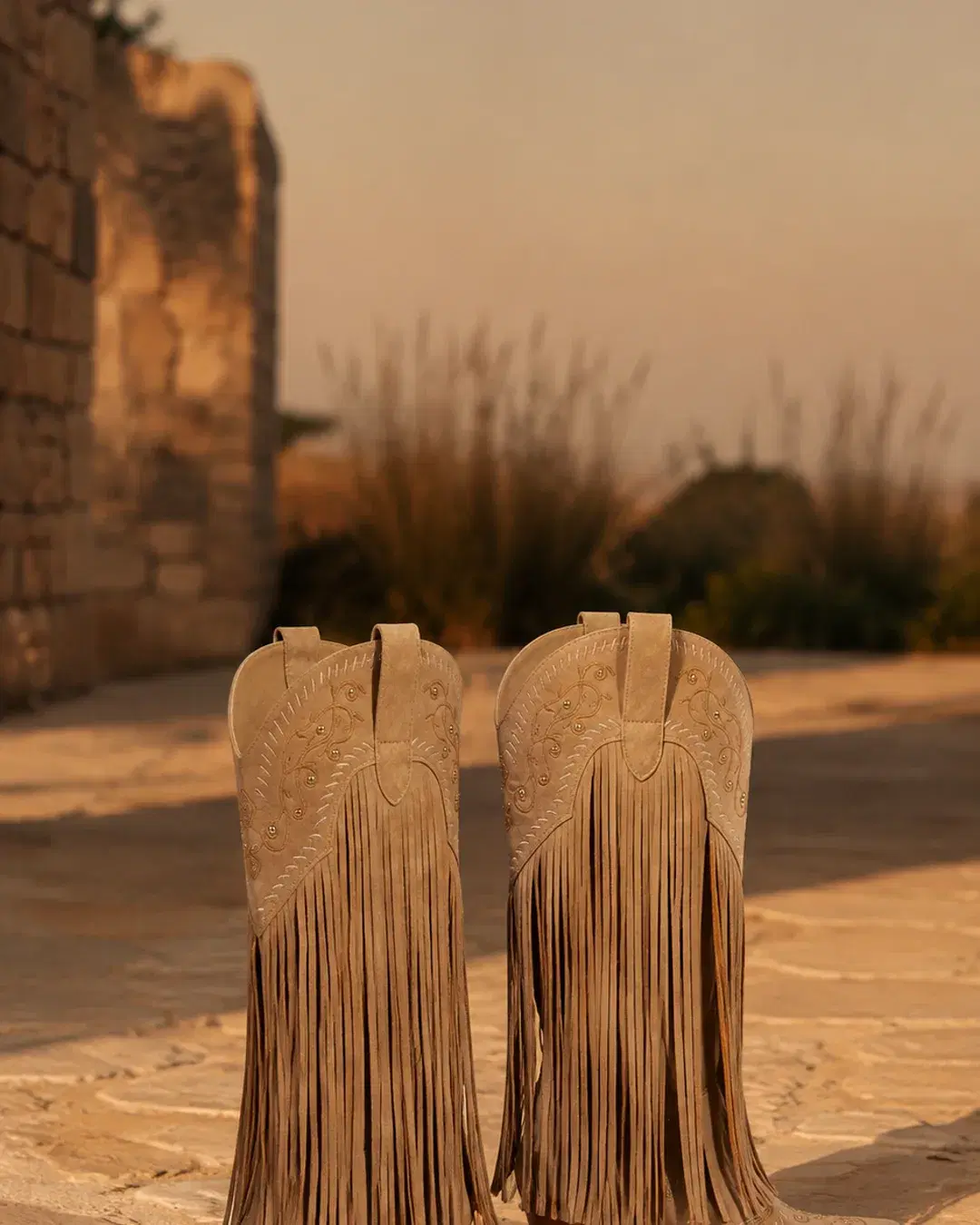 Both boots standing unworn on pale stone at dusk