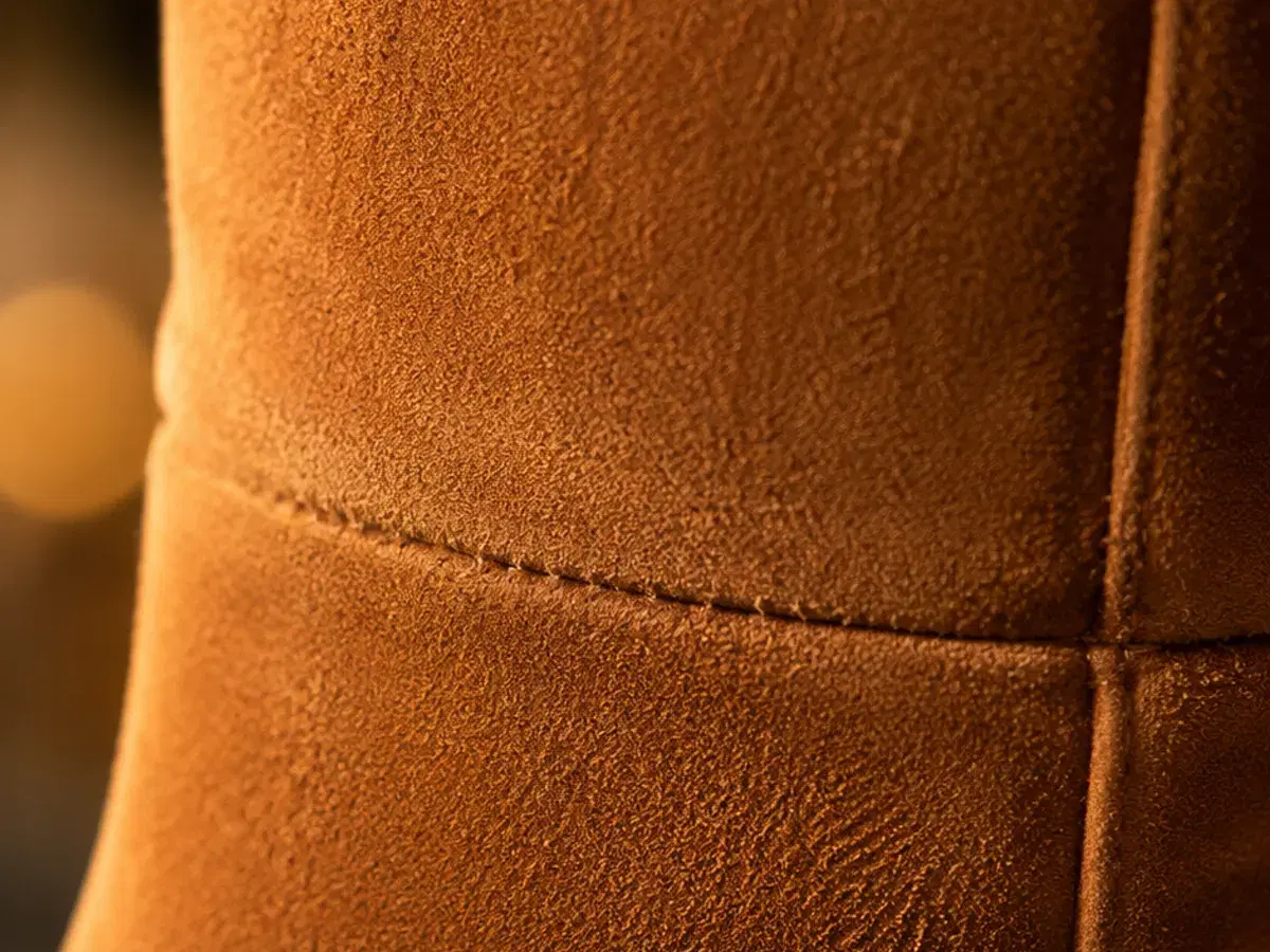 Macro detail of the cognac suede nap and the clean horizontal ankle seam