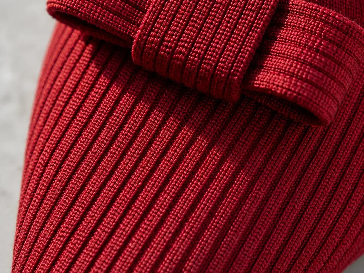 Macro detail of the fine vertical ribbed knit and the flat bow on the vamp