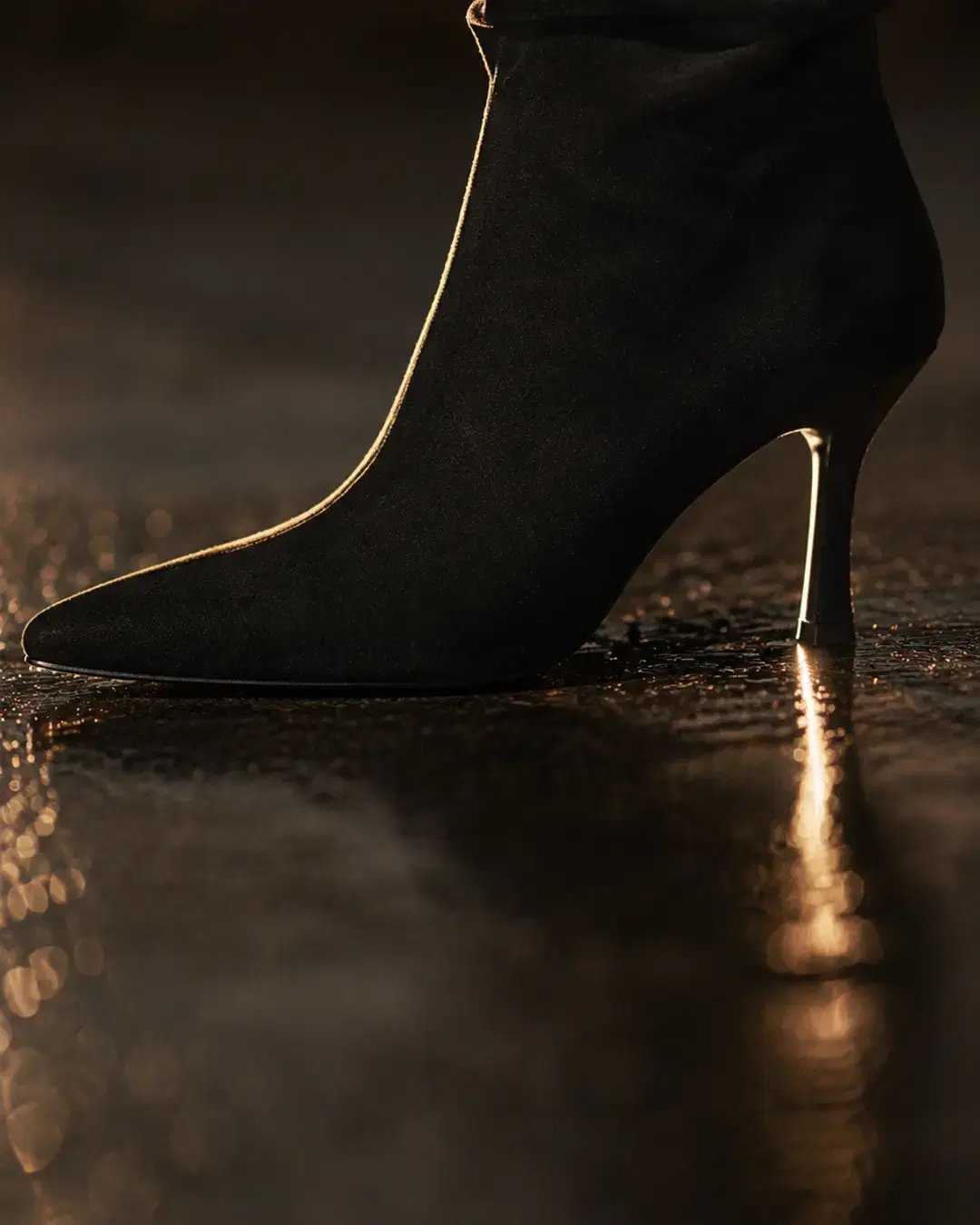 Close view of the pointed toe and slim tapered heel on wet pavement
