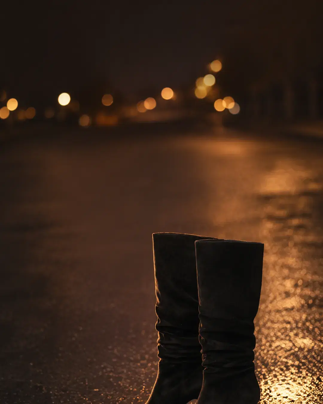 Both boots standing together on wet asphalt at dusk