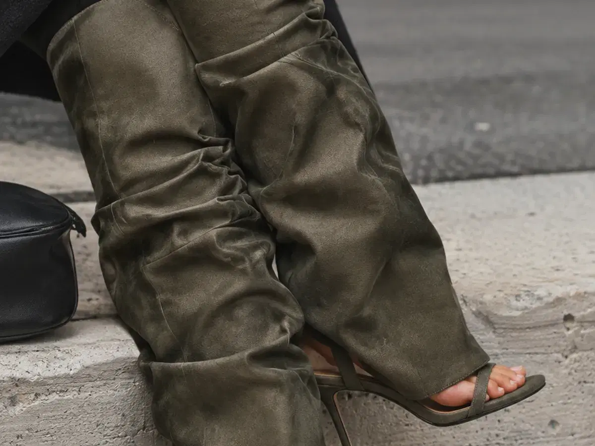 Seated on a stone kerb, showing the open toe and bare heel beneath the folded suede edge