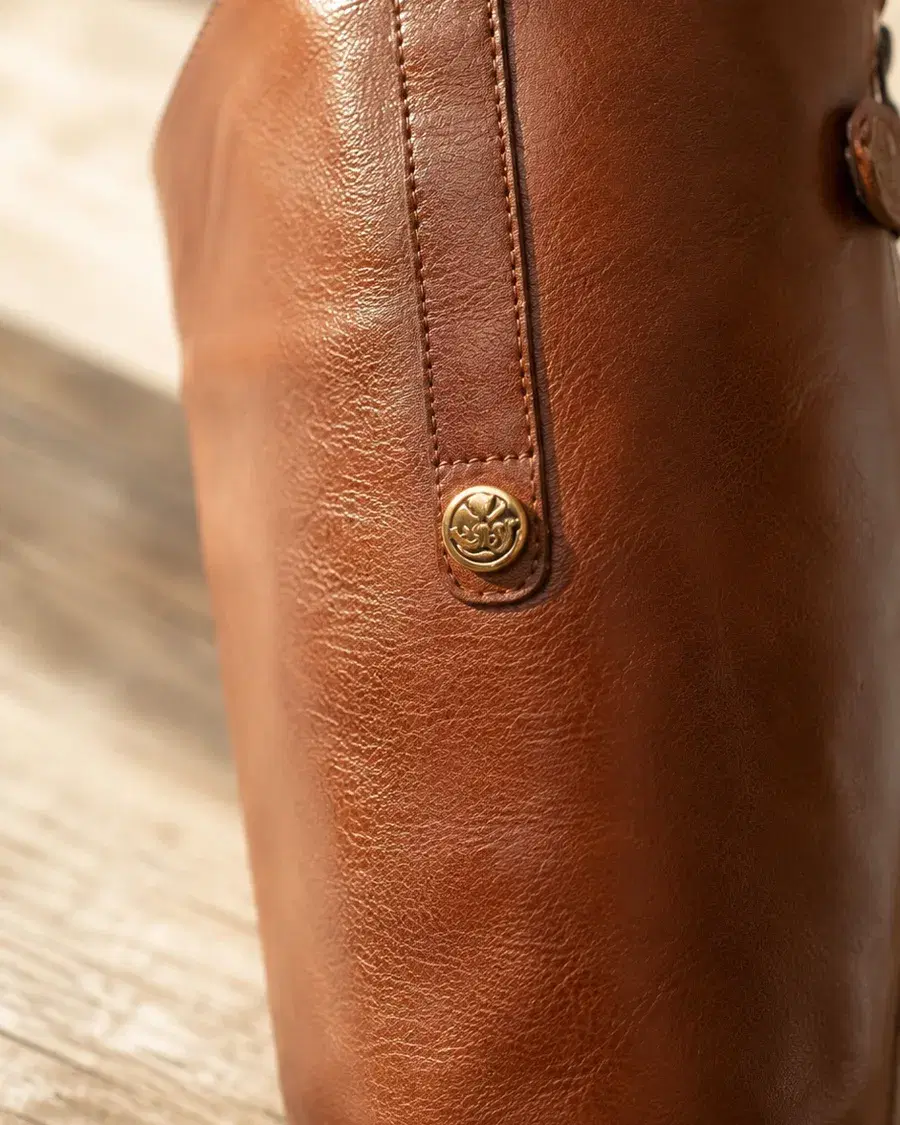 Macro detail of the gold logo button and leather grain on the Sam Edelman Penny