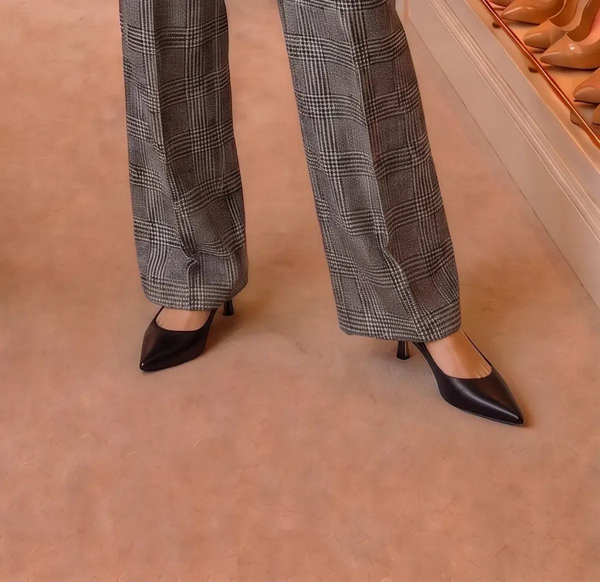 Black pointed kitten-heel slingbacks under grey plaid wide-leg trousers