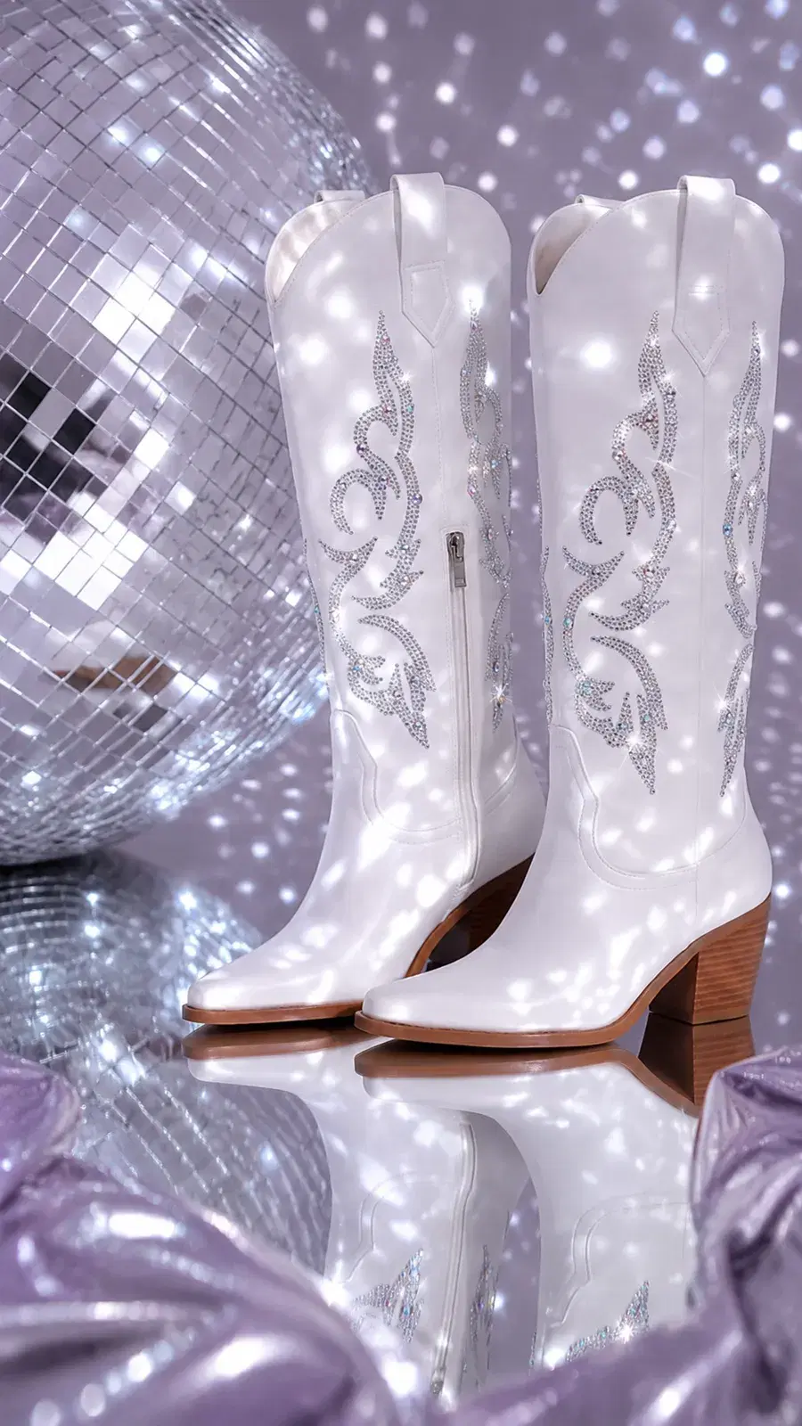 White rhinestone cowboy boots beside a disco ball with sparkling reflections